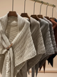Row of knit sweaters on hangers against a beige background