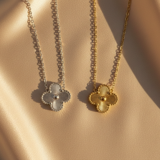 Two gold necklaces with floral ends on a beige fabric background