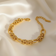 Gold chain bracelet on a soft beige fabric background