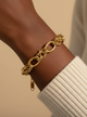 Gold chain bracelet on a wrist with a neutral background