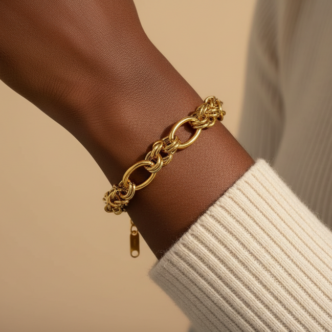 Gold chain bracelet on a wrist with a neutral background