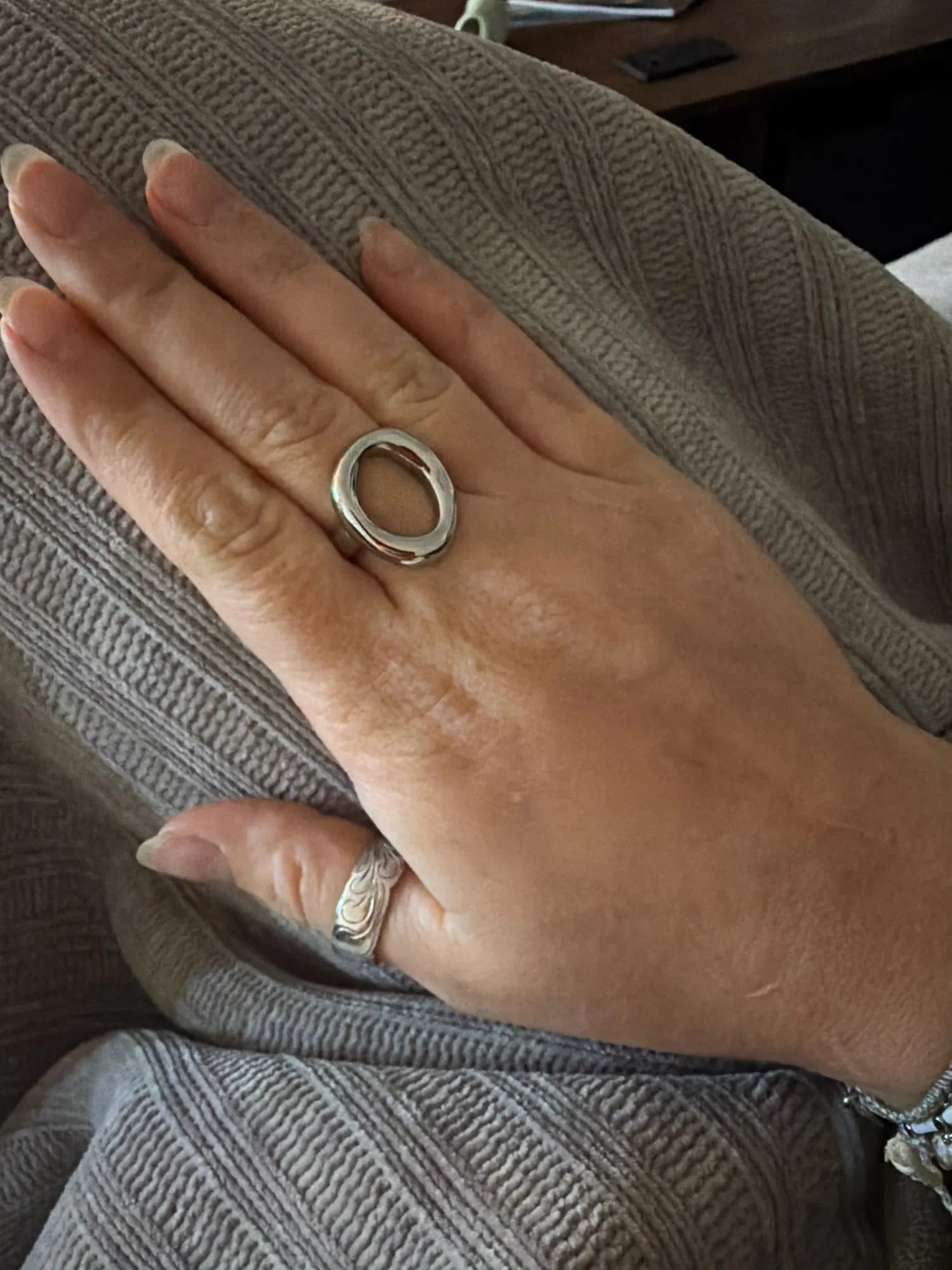 Silver abstract oval ring worn on a hand