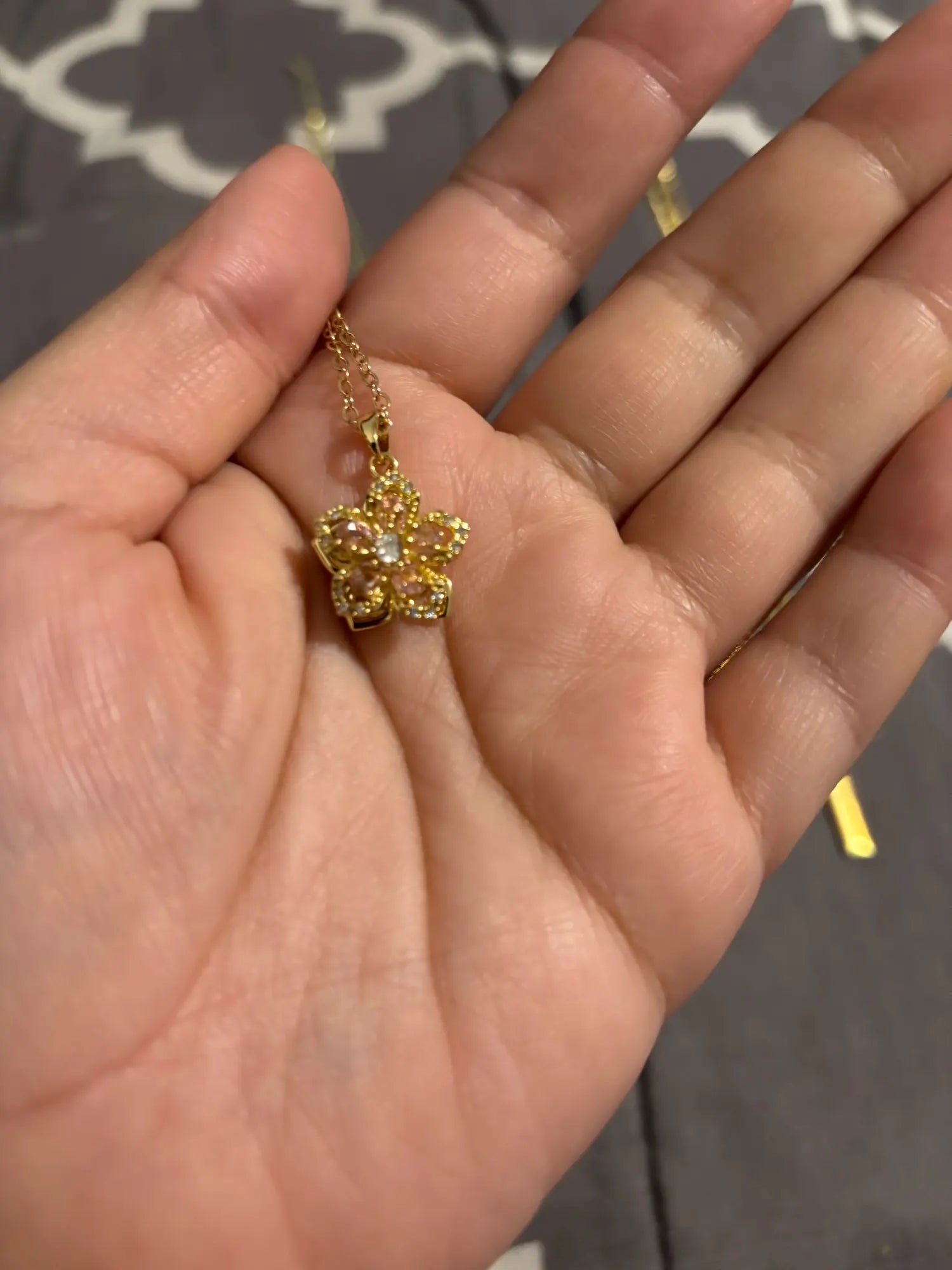 Pink rotating flower pendant held in a customer’s hand